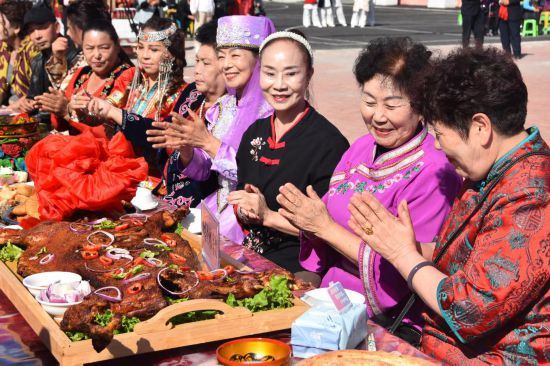 9月27日，在新疆塔城市新城街道哈尔墩社区举行的“邻里节百家宴”现场，居民在品尝各色美食。新华社记者 顾煜 摄